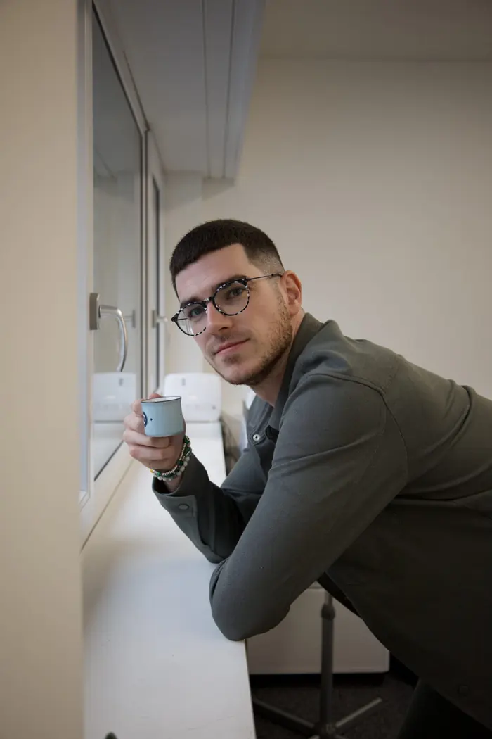 David Giannarelli réfléchissant près de la fenêtre, un café à la main