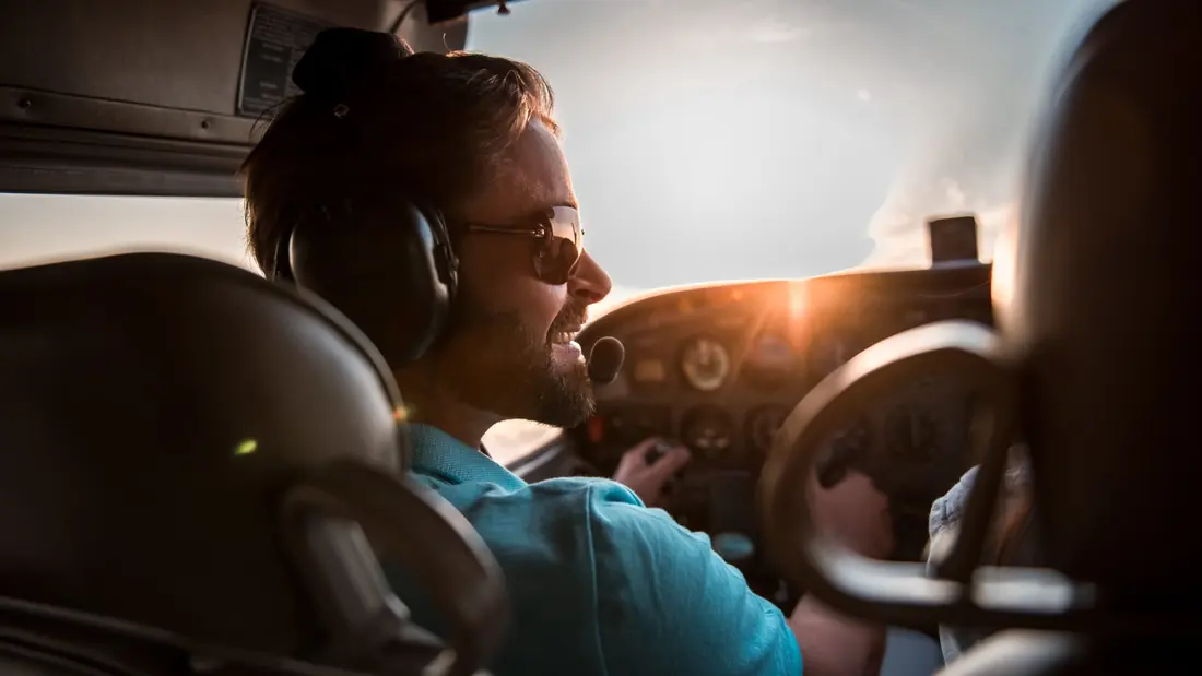 Pilote souriant aux commandes, casque audio sur les oreilles