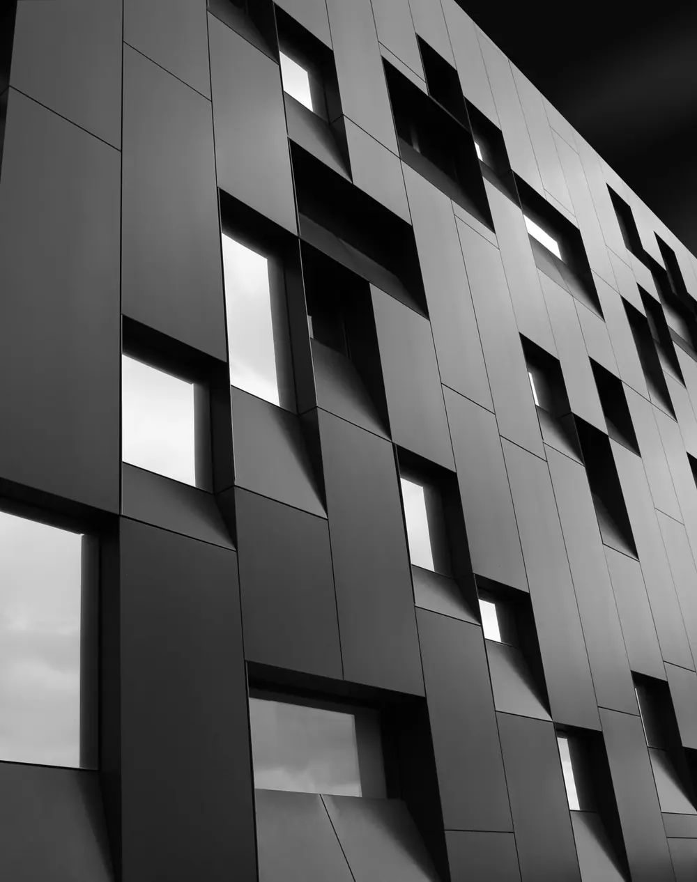 Façade d’immeuble moderne aux volumes sombres, vue en contre-plongée