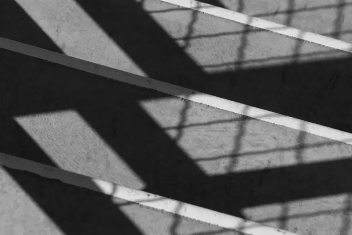 Jeux d’ombres géométriques sur une façade, photographiés en noir et blanc